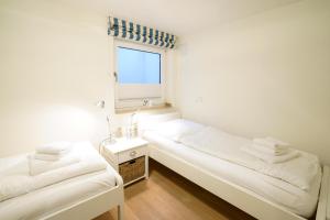 2 Betten in einem kleinen Zimmer mit Fenster in der Unterkunft Strandhaus WHG NR 1 "Meer Strand Und Design in Wenningstedt" in Wenningstedt-Braderup