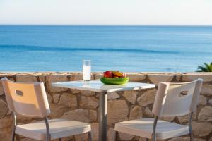 a table with a bowl of fruit and a glass of water at Caravella Luxury Apartments in Palaiochora