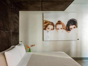 ミラノにあるME ミラノ イル ドゥーカの壁に女性の写真が2枚飾られたベッドルーム