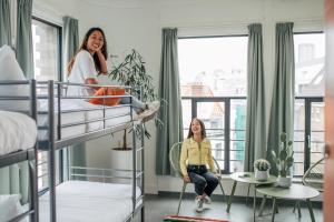 dwie dziewczyny w pokoju wieloosobowym z łóżkami piętrowymi w obiekcie Pink Flamingo Boutique Hostel w Hadze