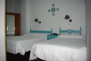 2 bedden in een slaapkamer met witte lakens bij Hotel Lanjaron in Lanjarón