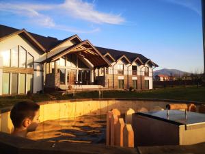 a boy in a swimming pool in front of a house at Cabana Chalet Transylvania in Orlat