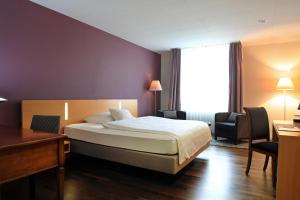 a hotel room with a bed, chair, and nightstand at Hotel Banana City Winterthur in Winterthur
