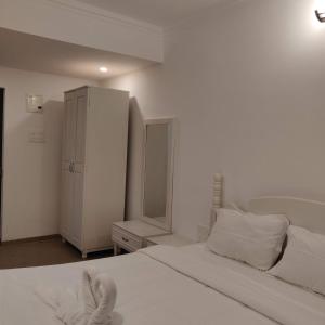a white bedroom with a bed and a cabinet at Studio Apartment by Leela Homes in Arpora