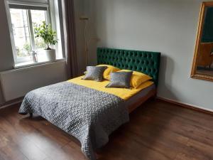 a bedroom with a bed with a green headboard at Kamienica Bydgoska in Bydgoszcz