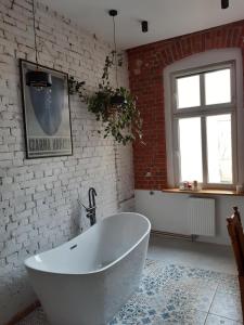 a white bath tub in a room with a brick wall at Kamienica Bydgoska in Bydgoszcz