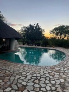 a swimming pool in a resort with a sunset in the background at Thula Private Lodge in Phalaborwa