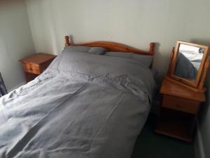Bett mit einem Kopfteil aus Holz neben einem Spiegel in der Unterkunft Acer Cottage in Bampton