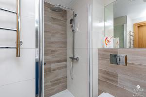 a shower with a glass door in a bathroom at Jantar Apartamenty - SeaView SEASIDE in Kołobrzeg