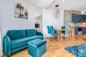 a living room with a blue couch and a table at Jantar Apartamenty - SeaView SEASIDE in Kołobrzeg