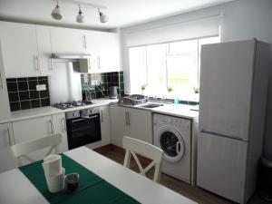 a kitchen with white cabinets and a washer at Acer Cottage in Bampton
