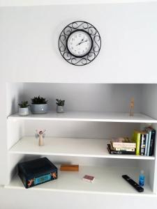 a white shelf with a clock and some books at Acer Cottage in Bampton