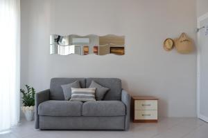 - un canapé gris dans le salon avec un miroir dans l'établissement B&B Hotel Oltremar, à Cattolica