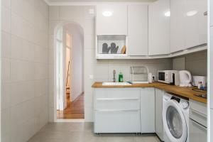 cocina con armarios blancos, lavadora y secadora en The Graceful Escape, en Lisboa