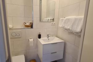 ein weißes Badezimmer mit einem Waschbecken und einem Spiegel in der Unterkunft B&B Het Groene Hart in Nieuwkoop