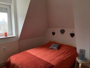 ein Schlafzimmer mit einem roten Bett und einem Fenster in der Unterkunft COSY APPART NUMERO 2 in Contrexéville