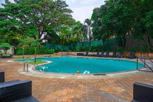 a swimming pool in a park with trees at Citrus Hotel Lonavala in Lonavala