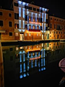 um edifício com luzes refletindo na água à noite em Ca' Bonfadini Historic Experience em Veneza