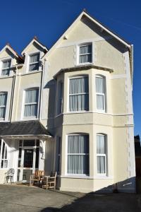 a white building with chairs in front of it at Cedar House, formerly Shamrock House in Llandudno