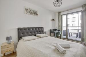 a bedroom with a large bed with two towels on it at Superbe appartement avec balcon et parking proche Paris in Saint-Denis