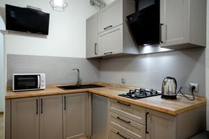 a kitchen with white cabinets and a stove and a microwave at Квартира в центре на соборной apartment in sobornaya st in Mykolaiv