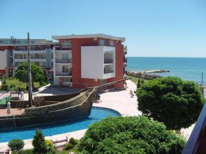 a red building with a boat in front of the ocean at GT Privilege Fort Beach Apartments in Elenite