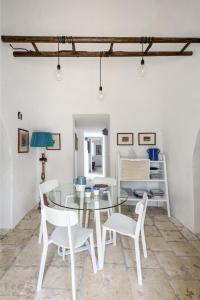 a dining room with a glass table and white chairs at le dimore di Ma Ma in Ceglie Messapica