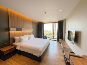 a hotel room with a bed and a television at The Teak Hotel in Mae Sot