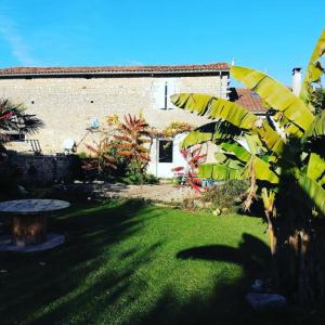 uma casa com um jardim verde com uma mesa em frente em Nid Charentais Angouleme pool jacuzzi em La Poterie