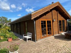 una cabaña de madera con un banco delante en Bij de Appelhof en Valkenswaard