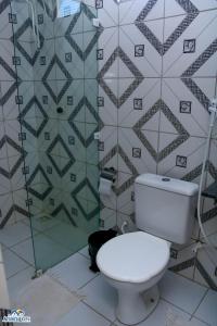 a bathroom with a toilet and a tiled wall at Pousada aconcheg'us in Jijoca de Jericoacoara