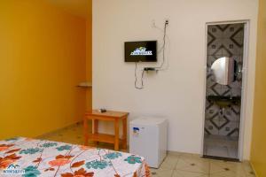 Habitación con cama y TV en la pared. en Pousada aconcheg'us en Jijoca de Jericoacoara