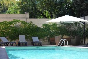 a swimming pool with chairs and an umbrella and a swimming pool at HRI Les Floridianes in Aix-en-Provence