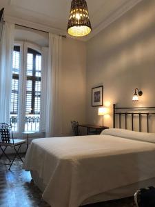 a bedroom with a large bed and a chandelier at Casa Consell Bailen, Guest House in Barcelona