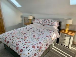 a bedroom with a bed with a floral comforter and two lamps at 31 Cherry East Riding of Yorkshire Hot Tub & Fishing in Garton +21 photos