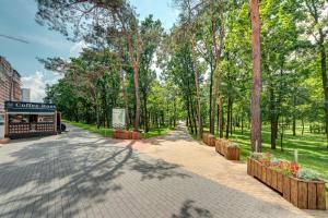 a tree lined street with a shop and trees at Apartment Voskresenska 18 , Парковые Озера in Kyiv