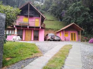 różowy dom z samochodem zaparkowanym przed nim w obiekcie Bangalô Boa Ventura w mieście Lumiar