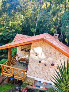 una piccola casa in mattoni con tetto e patio di Nas Nuvens Hospedaria a Monte Verde