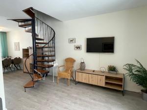 a living room with a television and a spiral staircase at Ferienhaus Küstelnest in Medebach