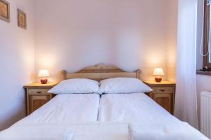 a bedroom with a bed with white sheets and two lamps at udanypobyt Apartamenty Skocznia in Zakopane