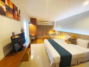 a hotel room with a teddy bear sitting on a bed at Crystal Jade Hotel in Rayong