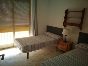 1 dormitorio con 2 camas y mesa con lámpara en Rpg en Benidorm