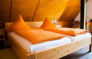 Dachsberg im SchwarzwaldにあるKlosterweiherhofの- オレンジ色の枕2つ(木製ベッドの上に座る)