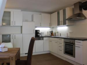 a kitchen with white cabinets and a wooden table at Ferienwohnung Staudacher in Rohrdorf