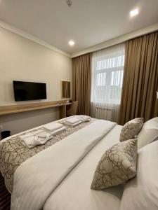 ein Hotelzimmer mit einem großen Bett und einem TV in der Unterkunft Bristol Hotel Tashkent in Taschkent