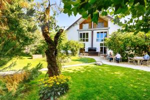 a house with people sitting at tables in a yard at Hôtel la Croix Blanche in Posieux