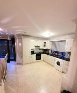 a large kitchen with white cabinets and a dishwasher at Westport Luxury Town House in Westport