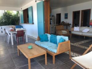a living room with a blue couch and a table at Villa GRENADINE - CLIM & TERRASSE- Face MER Vue panoramique, les pieds dans l'eau - OFFRE SPECIALE - LES SAINTES in Terre-de-Haut +14 photos