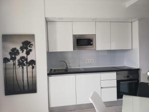 a white kitchen with a sink and a microwave at Apartamento la estrella, los cristianos in Los Cristianos