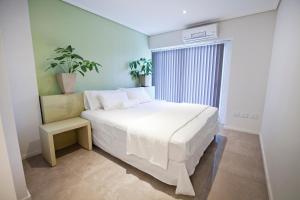 メンドーサにあるLe Montreal Apart Hotelの白いベッドと植物が備わるベッドルーム1室が備わります。